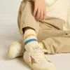 Getragene weiße Kindersocken mit Used-Details und zweifarbigen Streifen in leuchtendem Blau und Senfgelb Getragene weiße Kindersocken mit Used-Details und zweifarbigen Streifen in leuchtendem Blau und Senfgelb