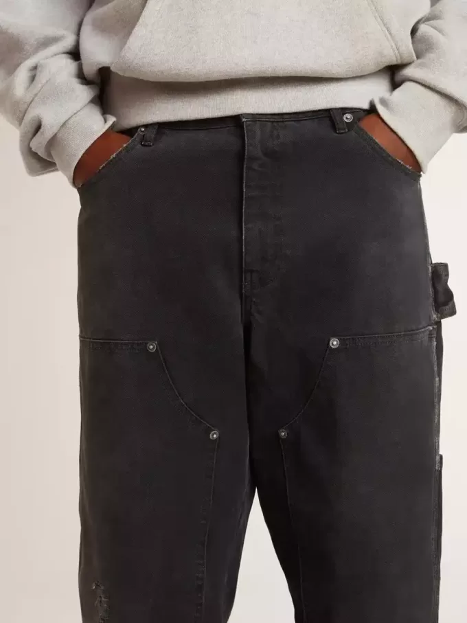 Herrenjeans aus schwarzem Baumwollstoff im Distressed-Look mit Aufnähern auf der Vorderseite Herrenjeans aus schwarzem Baumwollstoff im Distressed-Look mit Aufnähern auf der Vorderseite