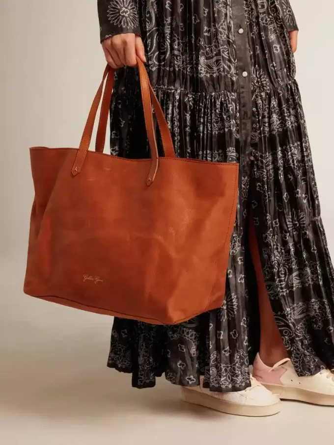 Pasadena-Tasche aus hellbraunem, glänzendem, gehämmertem Leder mit goldenem Logo auf der Vorderseite Pasadena-Tasche aus hellbraunem, glänzendem, gehämmertem Leder mit goldenem Logo auf der Vorderseite